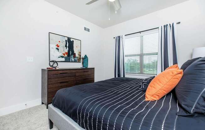 A bedroom with a bed, a dresser, and a painting on the wall.
