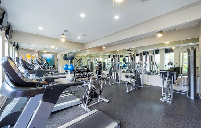 a gym with weights and cardio equipment in a building with windows