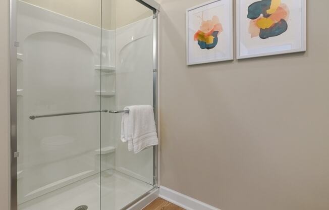 a bathroom with a glass shower and two paintings on the wall