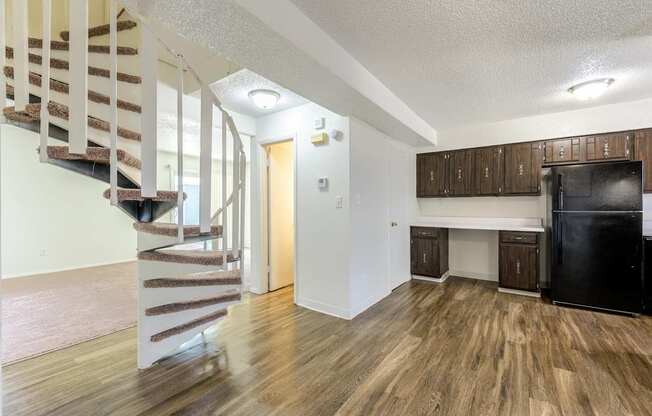 A kitchen area with a black fridge and wooden cabinets at Spring Creek Townhomes Apartments, Illinois 62702