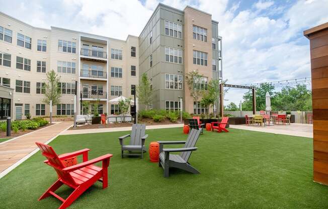 a courtyard with red chairs and lawn chairs in front of an apartment building