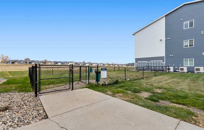 A fenced area with a sign and a building in the background.