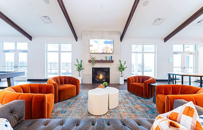 A living room with a fireplace and orange chairs.