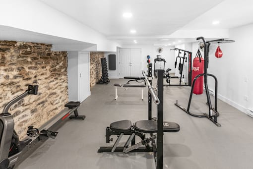 a gym with exercise equipment and a stone wall