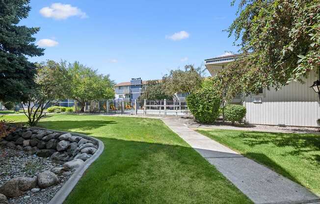 A well-maintained lawn with a stone pathway and a building in the background.
