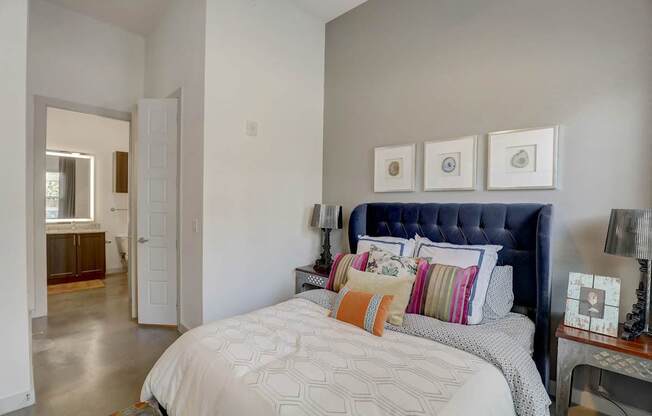 A bedroom with a large bed and a blue headboard at Infinity on the Point Apartments, Dallas, TX