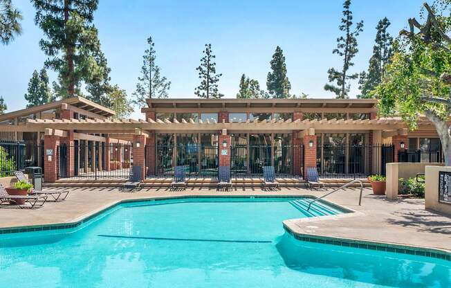 A large swimming pool in front of a building with a covered patio area.