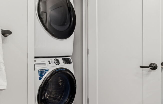 A white door is open to a laundry room with a washer and dryer.