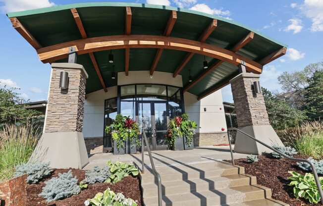 a view of the front entrance of a building with a green roof and brick pillars