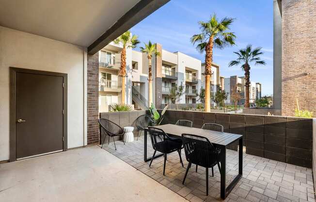A patio with a table and chairs overlooks a row of apartment buildings.