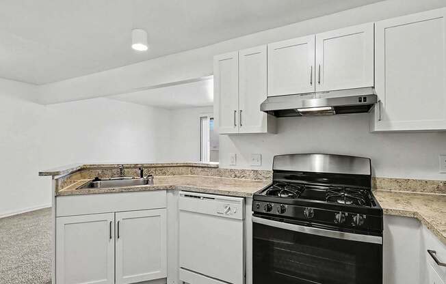 An upgraded kitchen with a dishwasher and white cabinets at Trappers Cove Apartments, Lansing