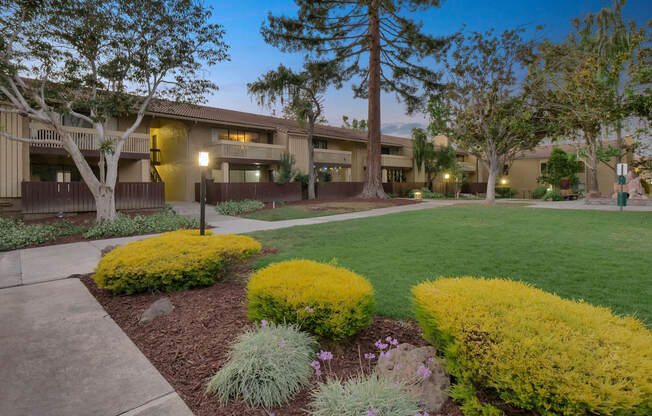 an exterior view of a building with green grass and trees at Summerwood Apartments, Santa Clara, California