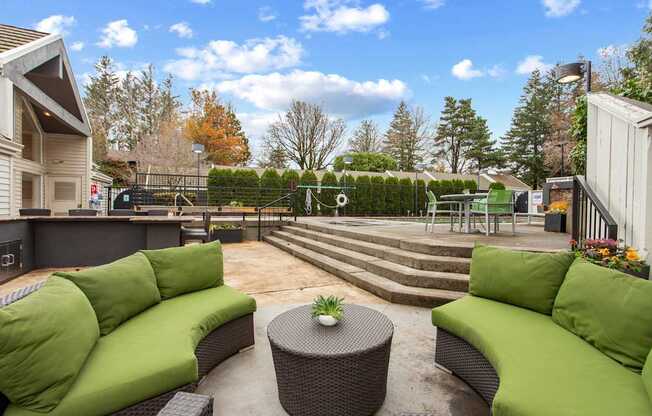 A patio with green couches and a table with a plant on it.