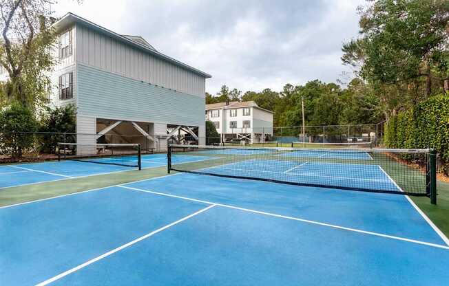 A tennis court is surrounded by a fence and a building.