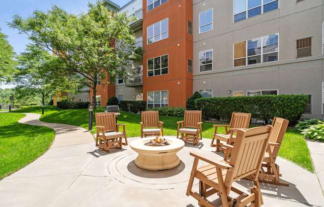 an outdoor patio with chairs and a fire pit in front of an apartment building