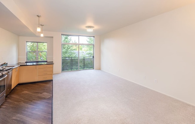 a spacious living room with a kitchen and a large window