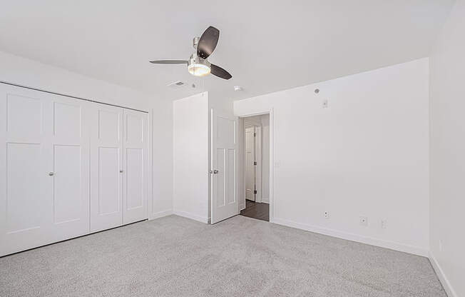 A bedroom with a ceiling fan and carpeted floor at Copper Creek Apartment Homes, Maize, Kansas
