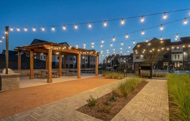 a patio with string lights and a wooden gazebo