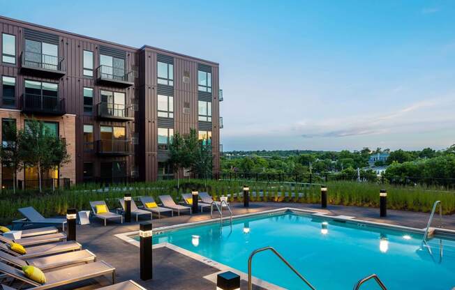 Rooftop pool deck looking out onto green St. Paul grounds. Pool is lined by lights and lounge seating.