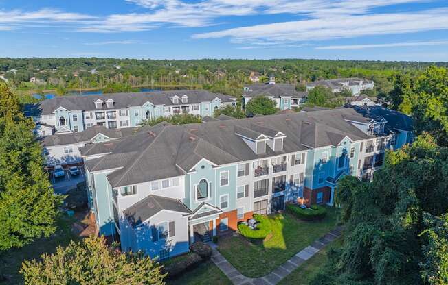 aerial view of the exterior of a large apartment building with green grass and trees