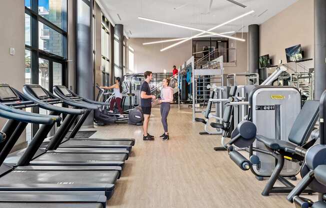 A gym with treadmills and people working out.