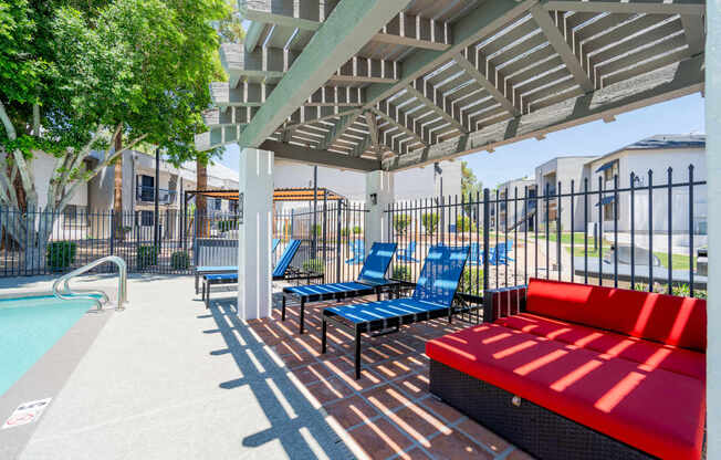 A pool area with a red bench and blue chairs.