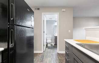 a kitchen with black appliances and a black refrigerator and a bathroom with a toilet