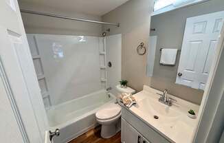 A white bathroom with a toilet, sink, and shower.