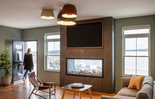 a living room with a fireplace and a woman walking through a door
