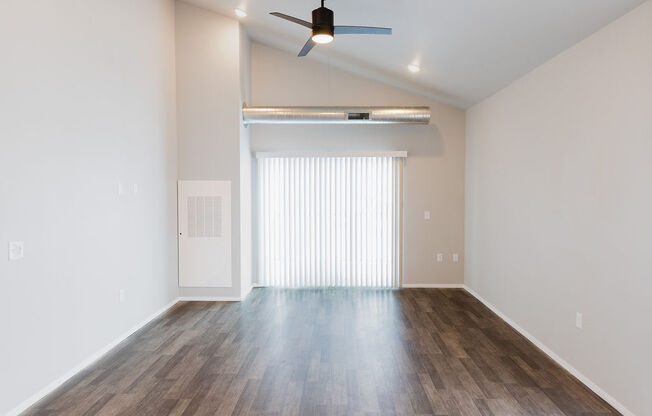 an empty living room with a ceiling fan and a window