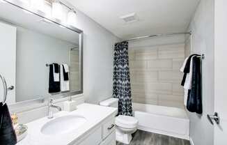 a bathroom with a white sink and toilet next to a white bathtub with a shower curtainat The Julia, Arizona