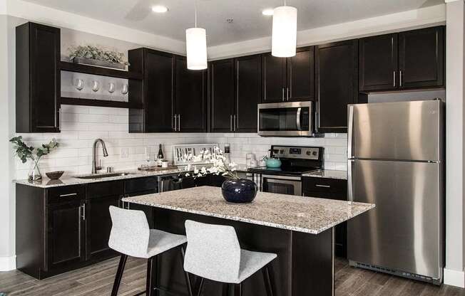 A modern kitchen with a granite countertop and stainless steel appliances.