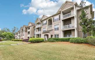 Apartment buildings with balconies and manicured green lawn .