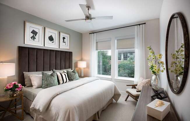 A bedroom with a large bed, a ceiling fan, and a mirror.