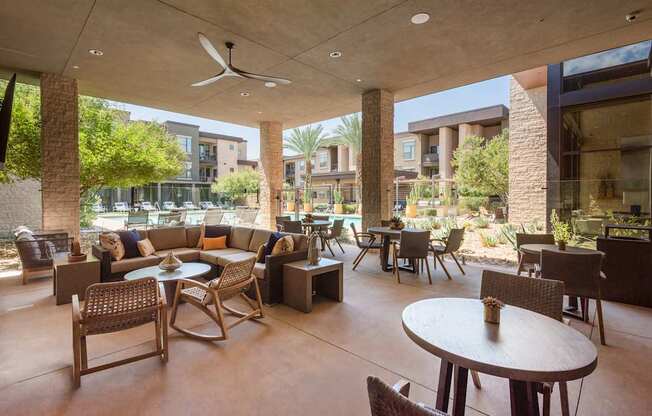 A patio with tables and chairs is surrounded by buildings.