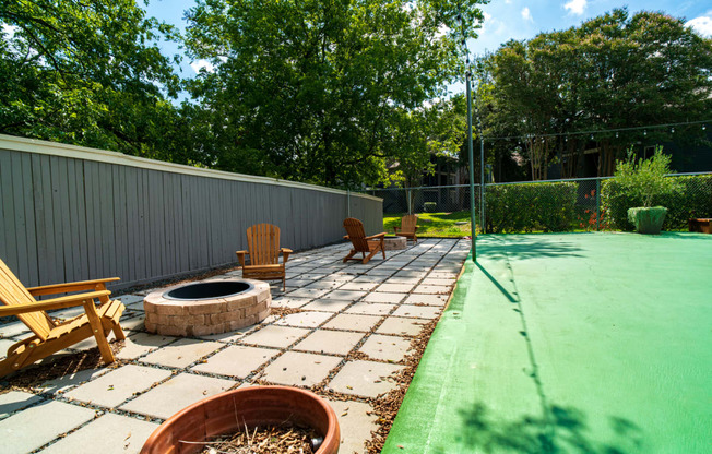 a backyard patio with a fire pit and chairs and a fence