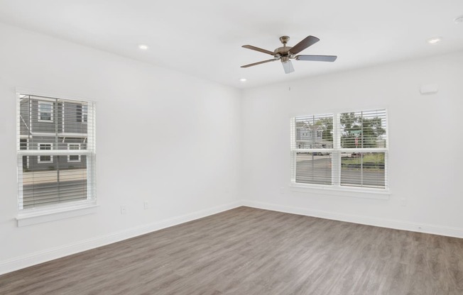 a living room with white walls and a ceiling fan