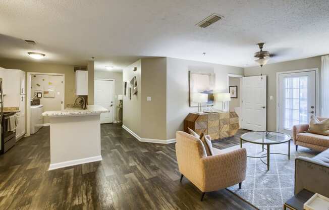 a living room and kitchen area with hardwood floors and a ceiling fan