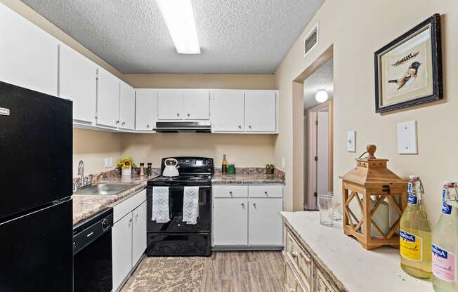 A kitchen with a black fridge and white cabinets.