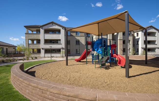a playground with a tent and slides in front of an apartment complex