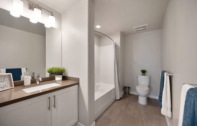 A bathroom with a sink, mirror, toilet, and bathtub.