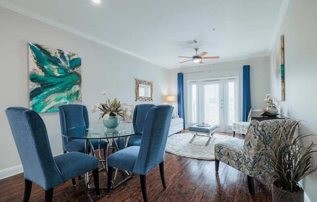 a living room with a glass dining room table with blue chairs