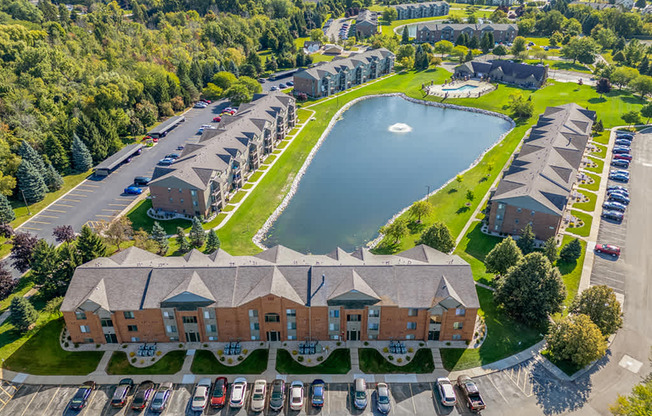 A drone view of buildings with a large pond at Oak Shores Apartments in Oak Creek, WI