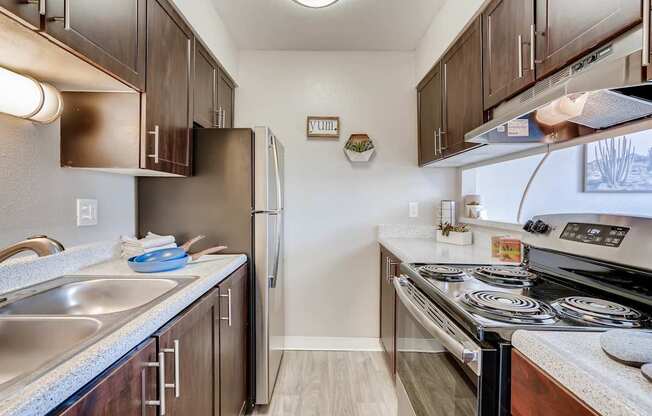 A kitchen with a stove top oven and a refrigerator at Mountain Vista Apartments, Lakewood