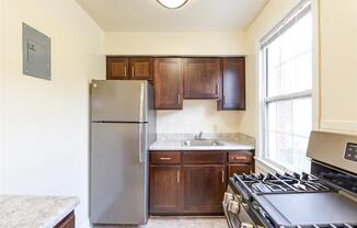 kitchen with espresso cabinetry, stainless steel appliances, gas range and window at the colonnade apartments in washington dc