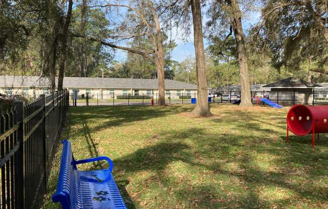 photo of a large grassy area with a swing set and a bench in front of a fence