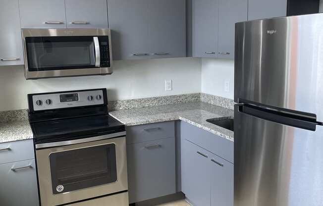 a kitchen with gray cabinets and stainless steel appliances at Colonial Apartments, Orlando, FL