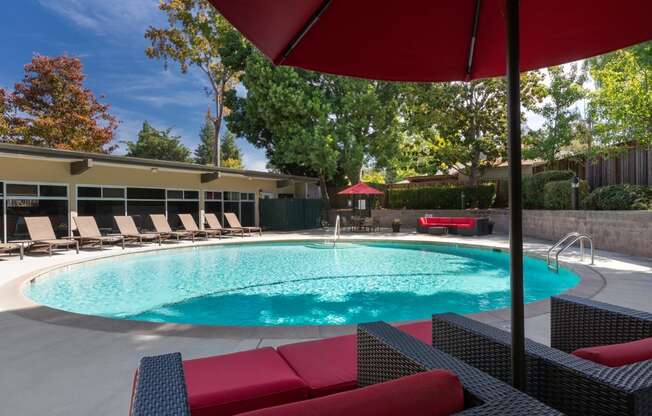 Apartments For Rent Palo Alto, CA - Refreshing Pool With Lounge Chairs, Couch, Tables With Umbrellas, And Lush Landscaping