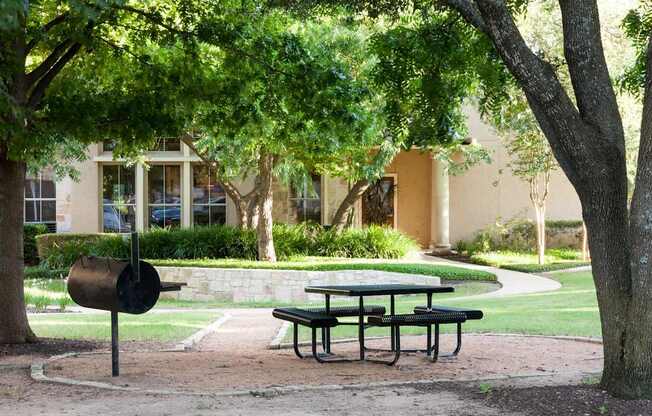 A picnic table is set up under a tree in a park.