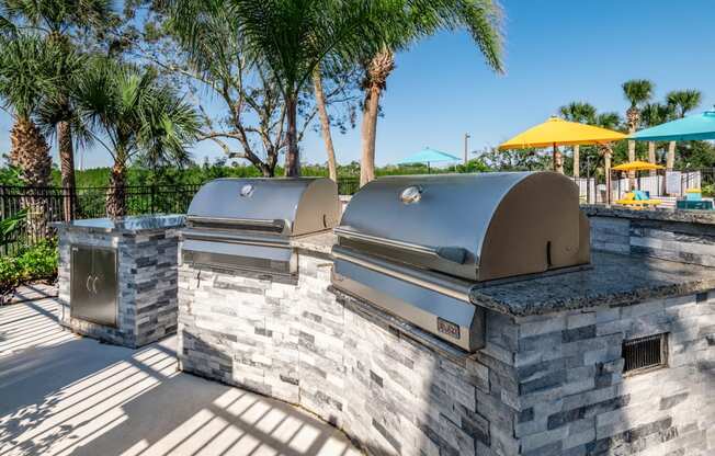 a bbq area with two grills and a table with umbrellas in the